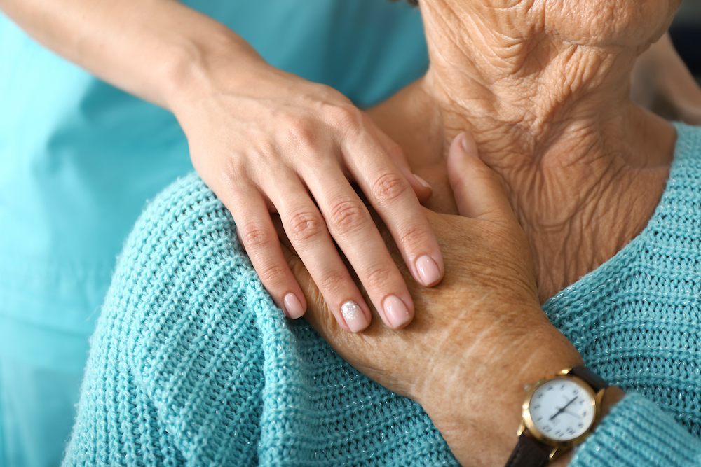 A caregiver and a senior resident hold hands at the memory care in Vista