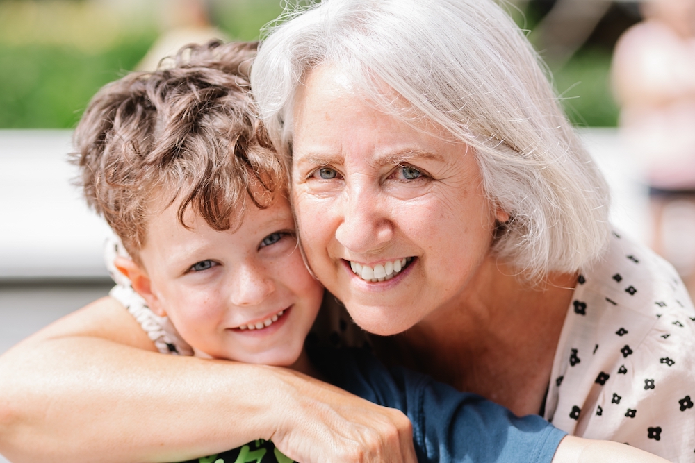 A senior woman hugs her grandson close for a photo